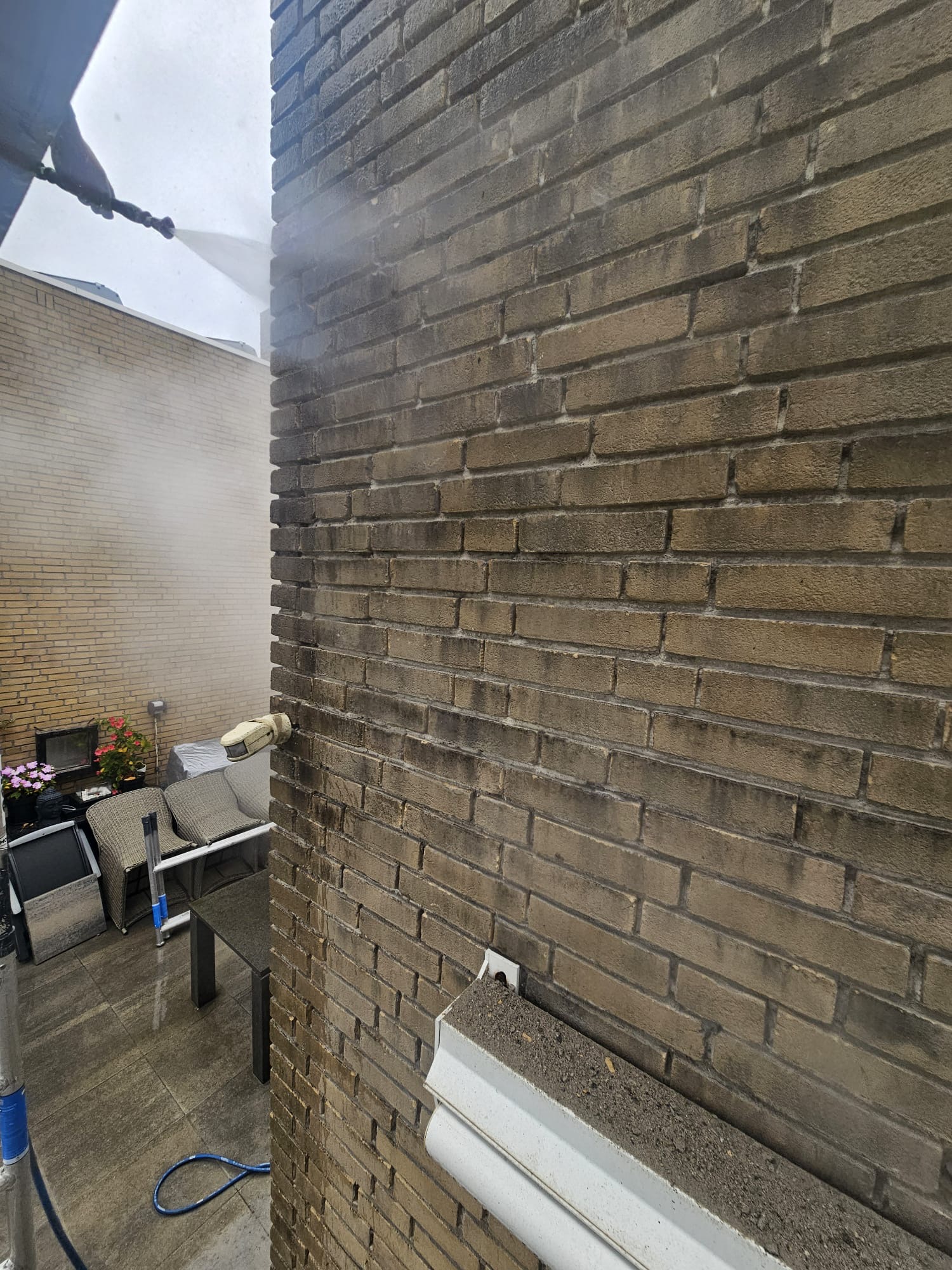 Gevelreiniging van donkere bakstenen zijmuur met hogedruk en waternevel Vervuilde bakstenen gevel professioneel laten reinigen in Den Haag