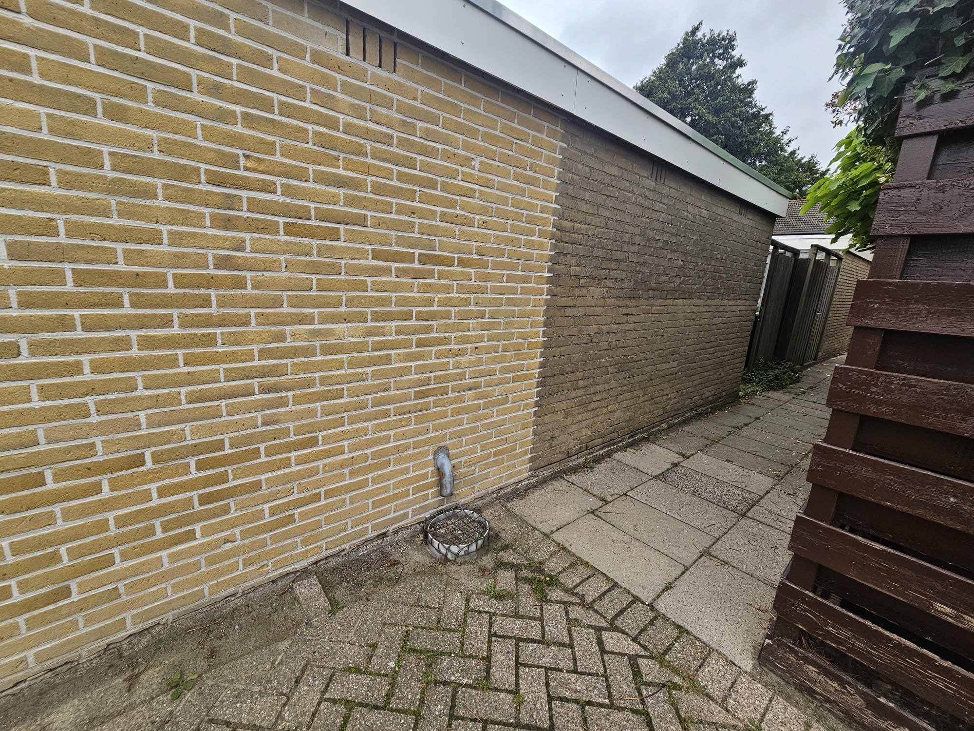 Gevelreiniging van gele bakstenen zijmuur met zichtbaar verschil tussen schoon en vervuild metselwerk Gevelreiniging van bakstenen gevel in Westland