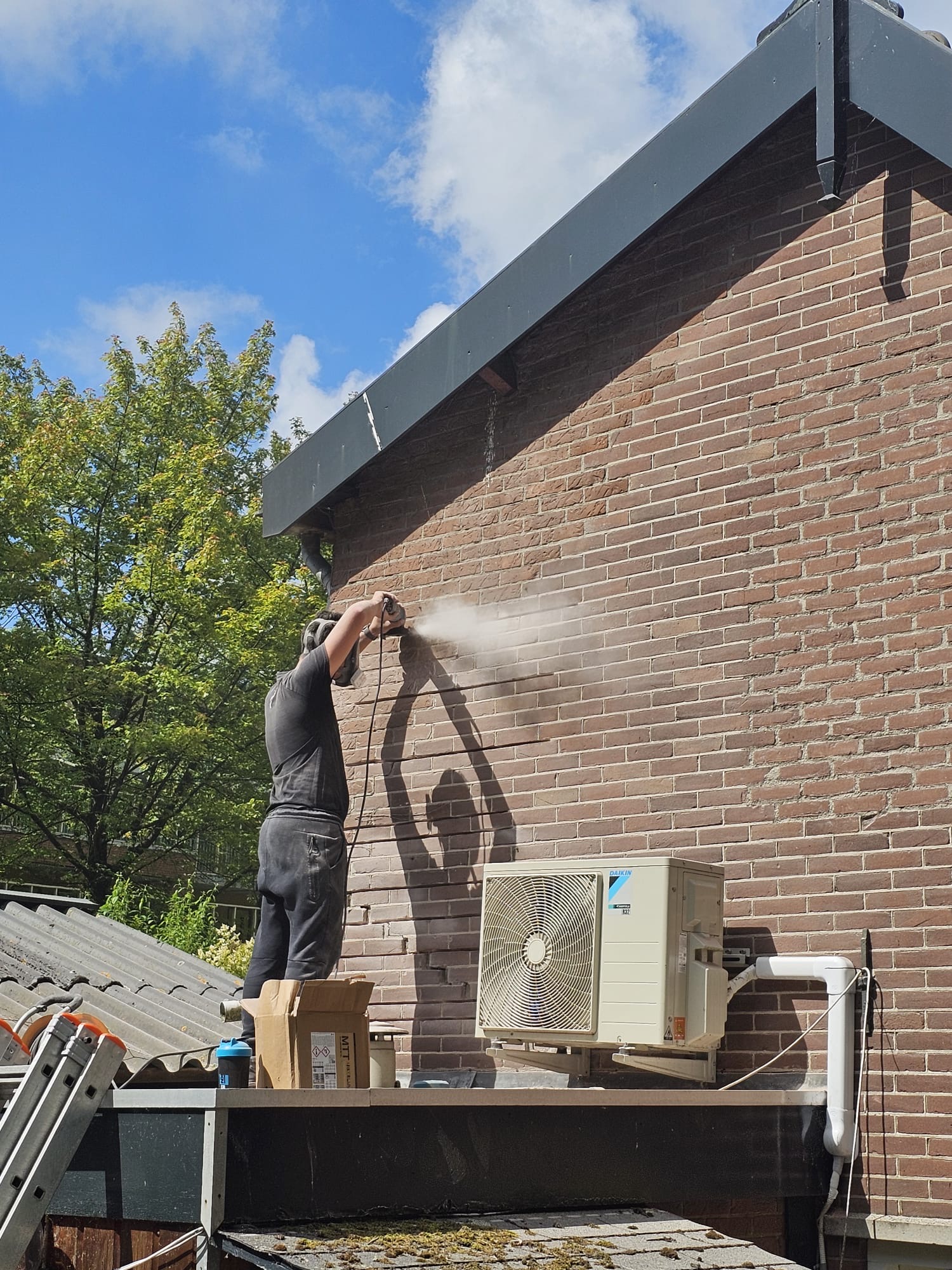 Gevelreiniging van rode bakstenen zijmuur onder zwarte dakrand Gevel reinigen door vakman in Zoetermeer