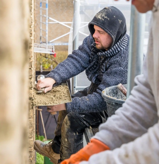 OVER ONS - man bij muur Steigerbouw