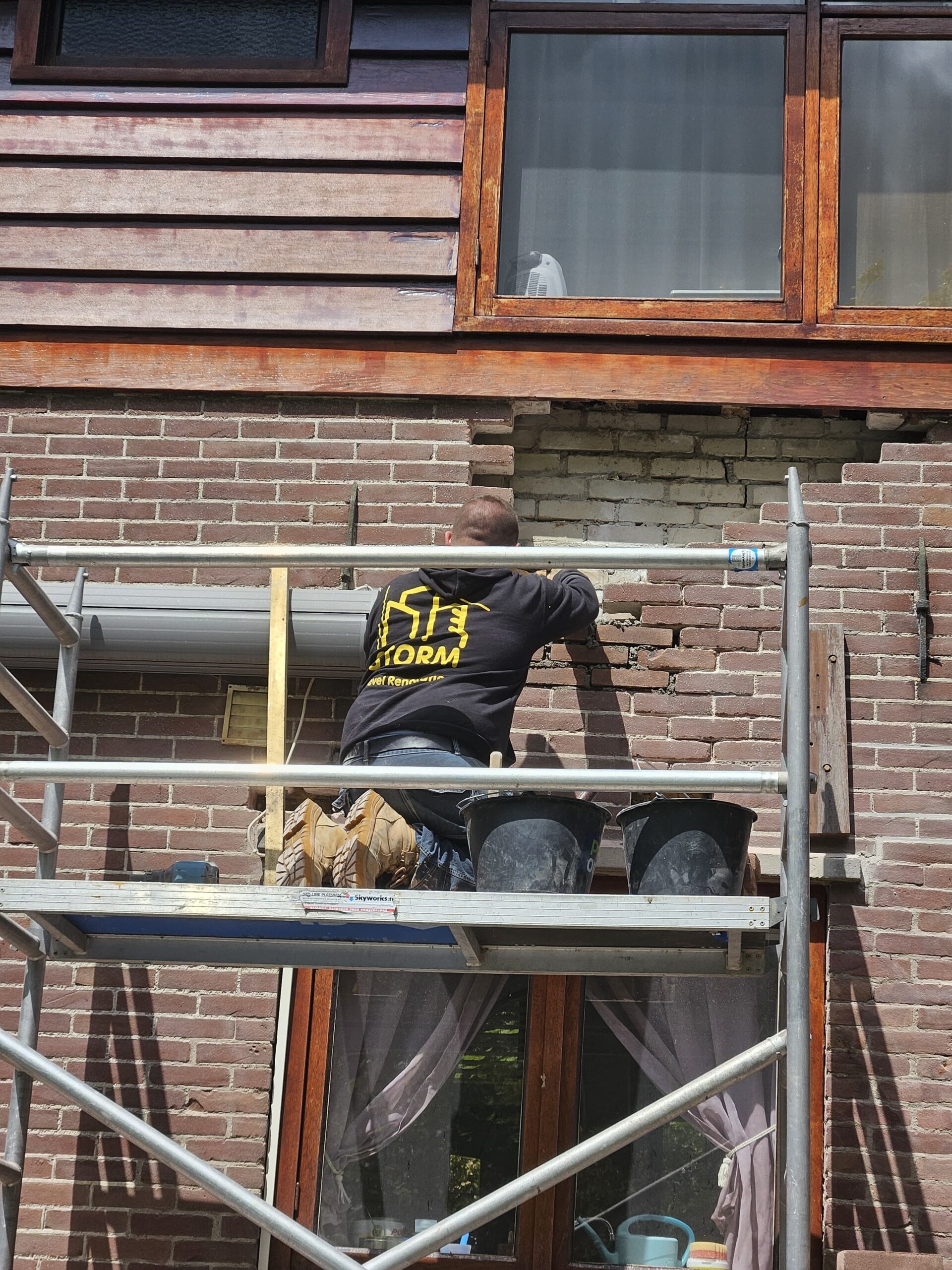 Renovatie van oudere woninggevel met houten gevelbekleding en bakstenen ondergevel Onderhouden woninggevel met houten gevelbekleding en schilderwerk