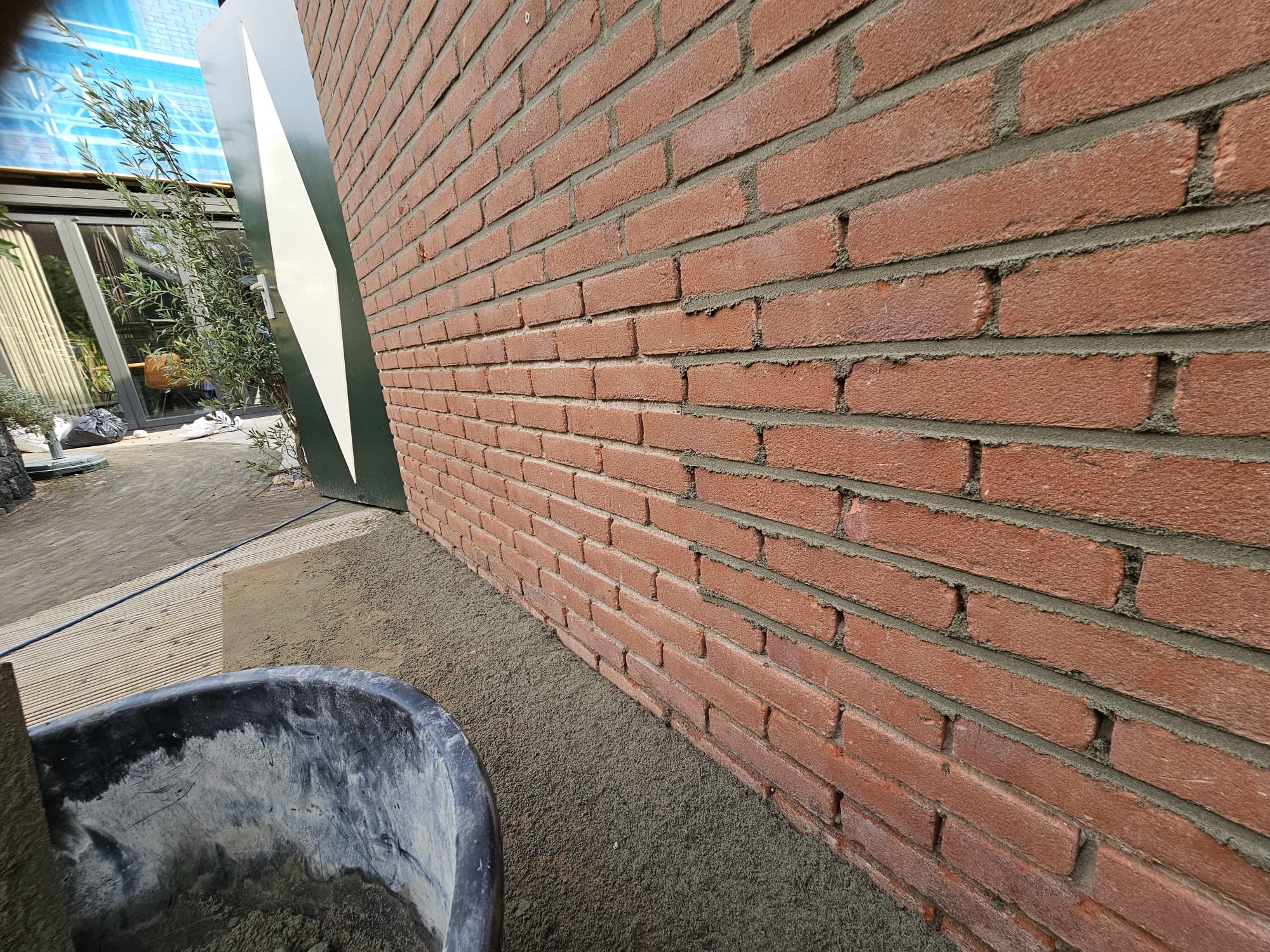 Rode bakstenen zijgevel met hersteld voegwerk langs woning of bedrijfspand Oud voegwerk zorgvuldig verwijderen uit een bakstenen gevel