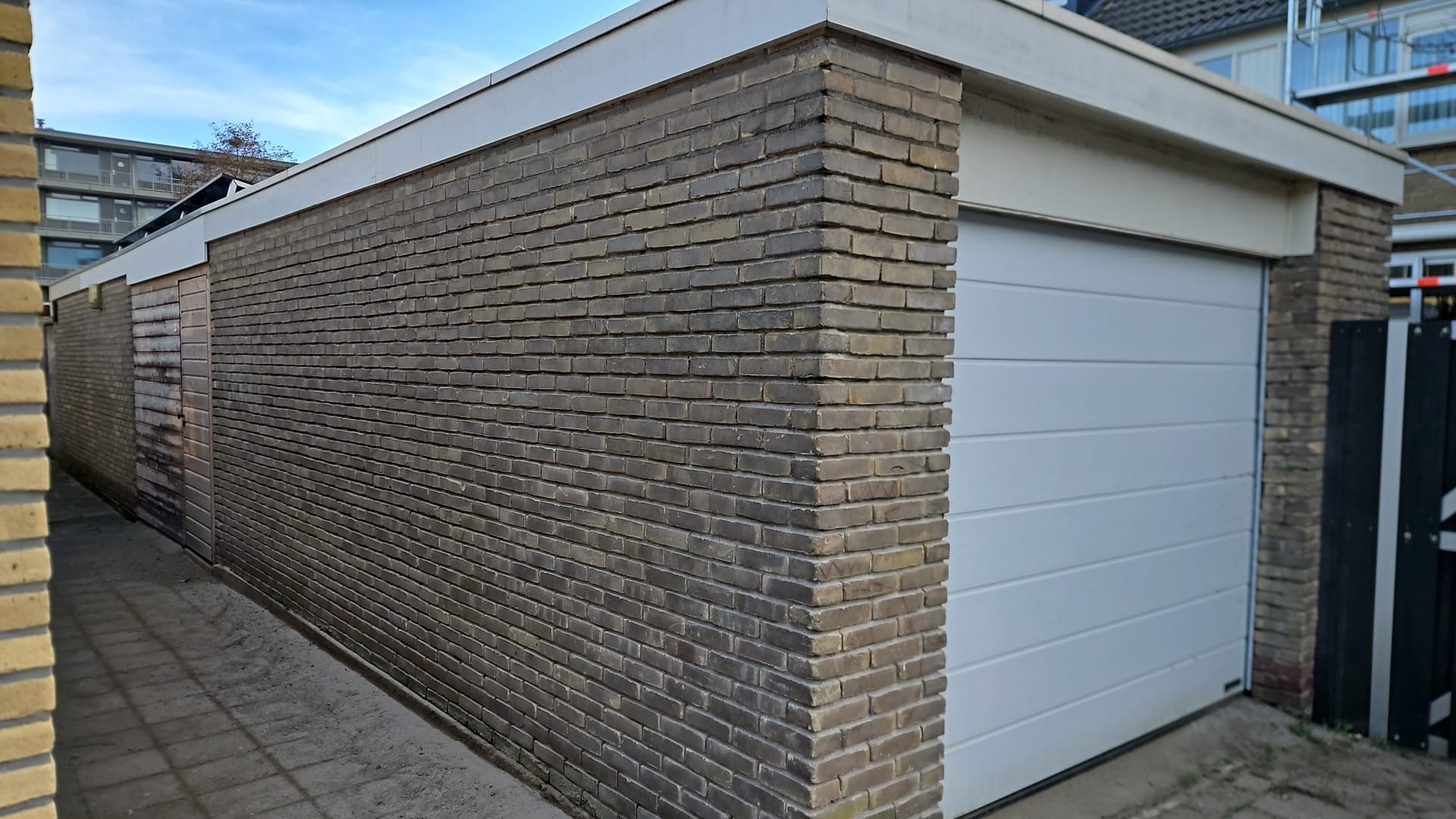 Verouderde bakstenen hoekgevel naast garage met zichtbaar voegwerk Verouderde bakstenen hoekgevel met zichtbaar metselwerk en voegwerk