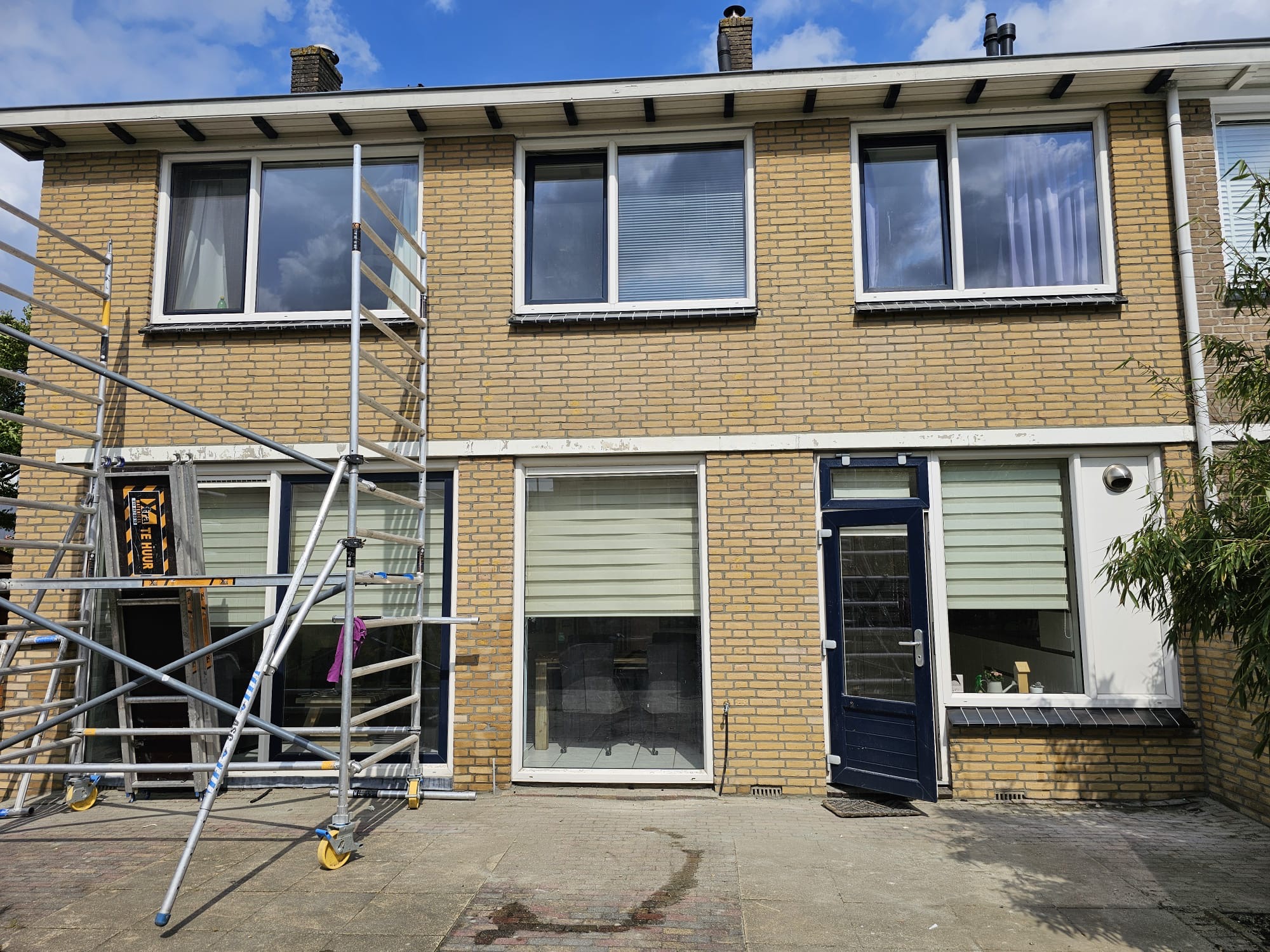 Voorgevel van rijwoning met steiger voor onderhoud aan metselwerk en kozijnen Voorgevel van rijwoning met steiger voor gevelonderhoud en constructief herstel