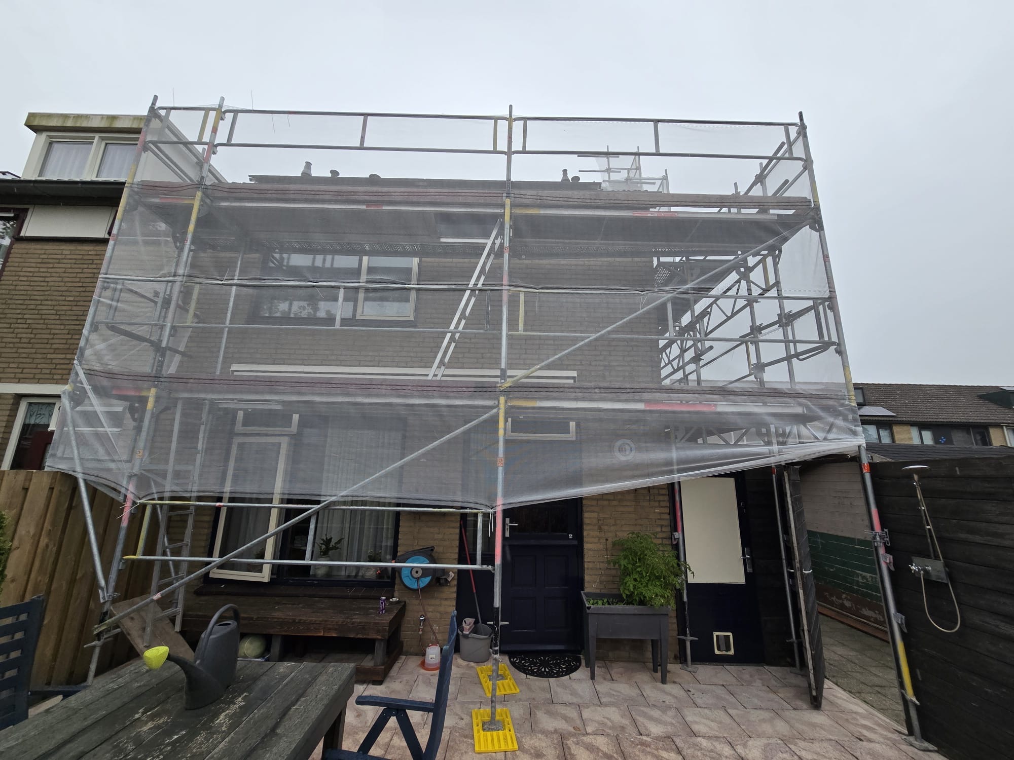 Woning volledig in de steigers met steigerdoek voor gevelrenovatie en onderhoud Woning in de steigers voor gevelrenovatie in Dordrecht